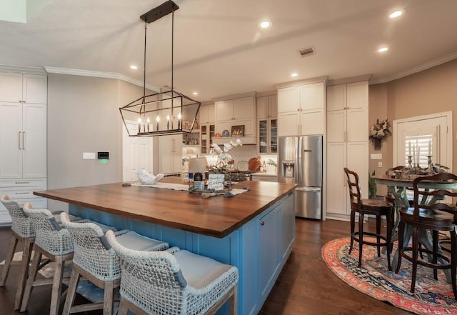 kitchen featuring stainless steel fridge with ice dispenser, wood counters, crown molding, a large island, and dark wood-style flooring