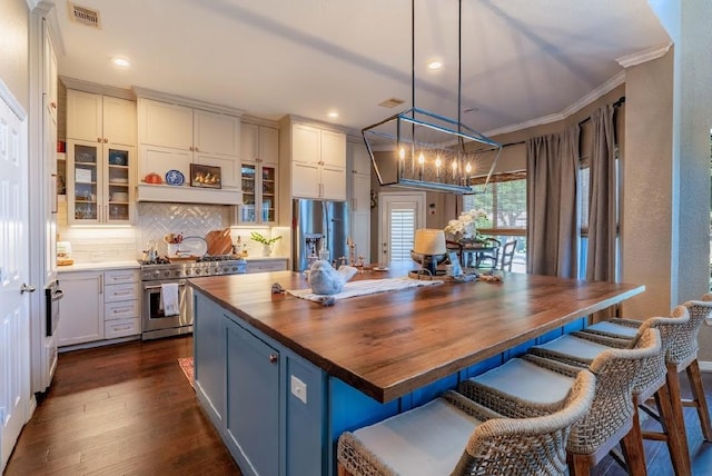 kitchen with stainless steel appliances, butcher block countertops, backsplash, dark wood-style flooring, and a chandelier