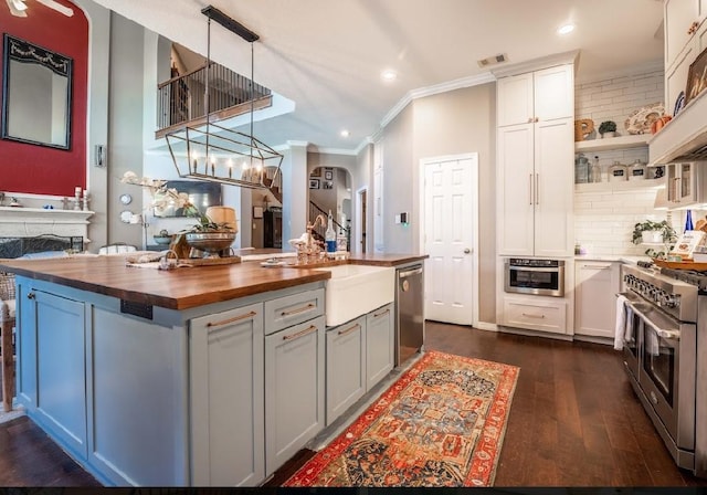 kitchen with wood counters, stainless steel appliances, ornamental molding, dark wood finished floors, and open shelves