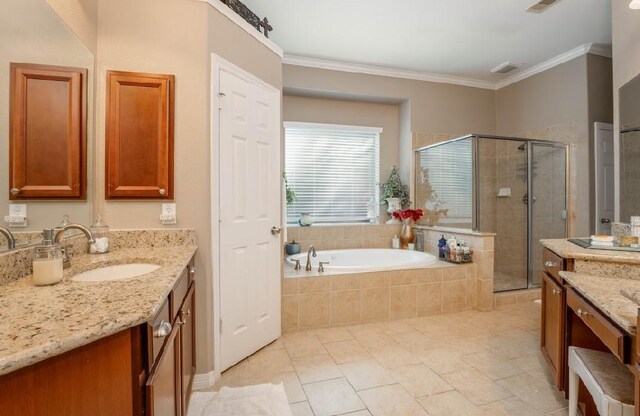 full bath featuring a bath, a shower stall, vanity, crown molding, and tile patterned floors