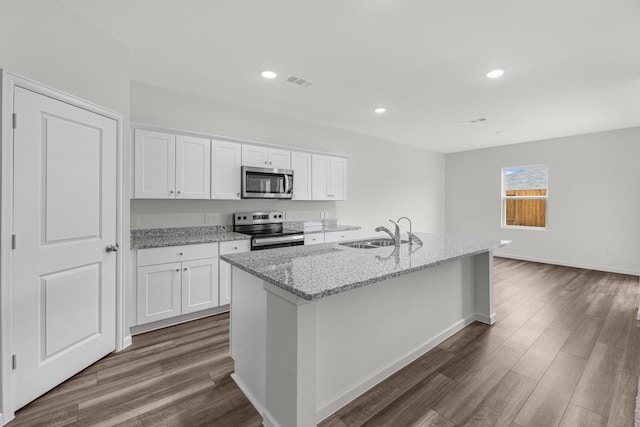 kitchen with appliances with stainless steel finishes, a sink, dark wood-style floors, white cabinets, and recessed lighting