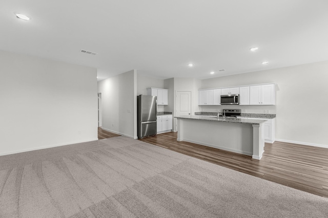 kitchen with appliances with stainless steel finishes, baseboards, recessed lighting, open floor plan, and white cabinets