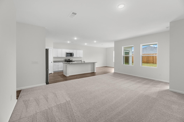 unfurnished living room with recessed lighting, baseboards, and carpet flooring