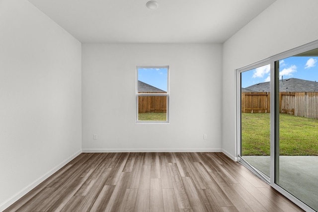 spare room with wood finished floors, healthy amount of natural light, and baseboards