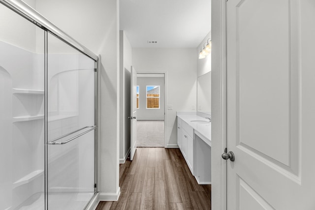 full bathroom featuring wood finished floors, vanity, a shower stall, and baseboards