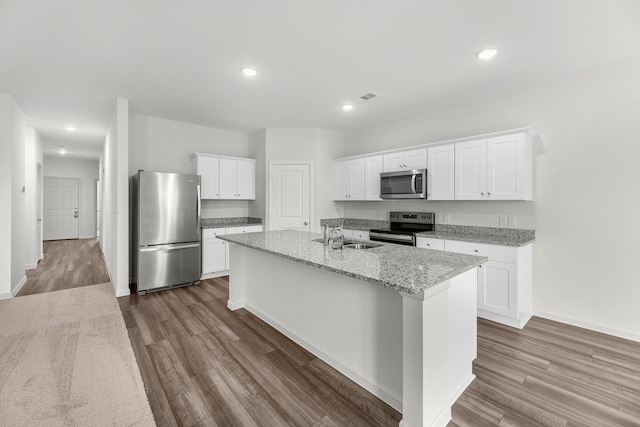 kitchen featuring stainless steel appliances, a sink, wood finished floors, a center island with sink, and recessed lighting