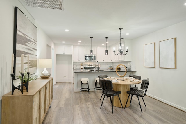 dining space featuring light wood finished floors, baseboards, a chandelier, and recessed lighting
