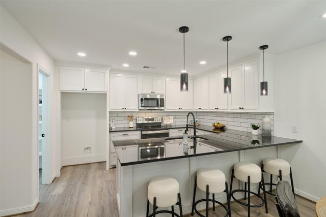 kitchen with appliances with stainless steel finishes, a sink, dark countertops, a peninsula, and baseboards