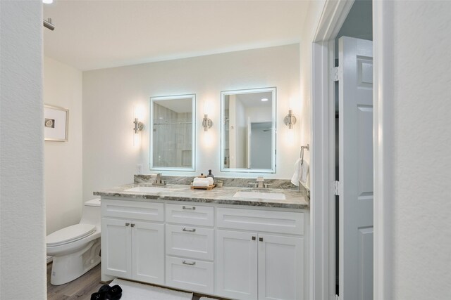 bathroom featuring toilet, wood finished floors, and double vanity