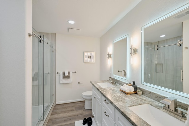 full bath featuring a stall shower, wood finished floors, toilet, double vanity, and recessed lighting