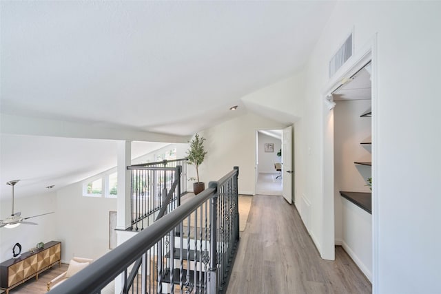 corridor with light wood-style floors, an upstairs landing, and baseboards