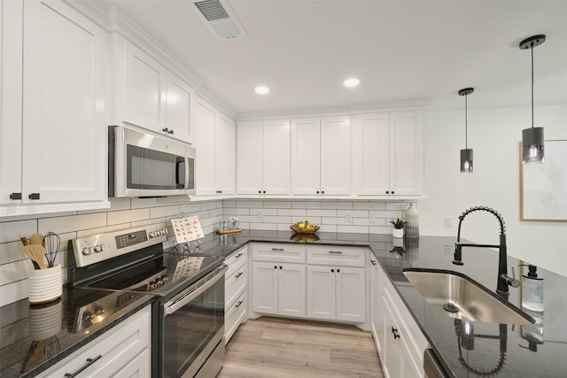 kitchen featuring appliances with stainless steel finishes, a sink, white cabinetry, tasteful backsplash, and recessed lighting
