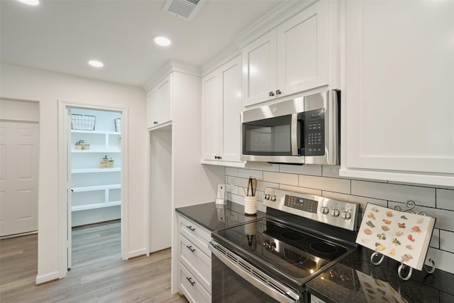 kitchen featuring stainless steel appliances, light wood finished floors, backsplash, white cabinetry, and recessed lighting