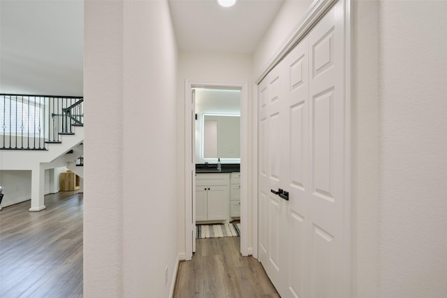 hallway featuring light wood-type flooring, stairs, and a sink
