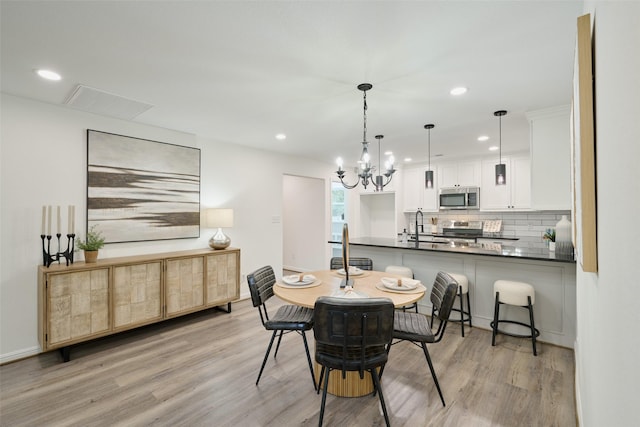 dining space with light wood-style flooring, recessed lighting, a chandelier, and baseboards