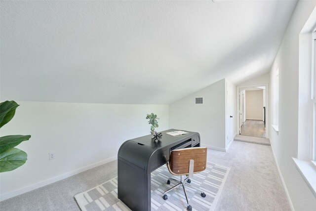 office area featuring lofted ceiling, light colored carpet, and baseboards