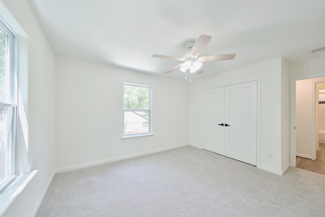 unfurnished bedroom featuring light carpet, baseboards, a closet, and ceiling fan
