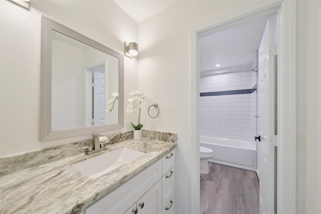 bathroom with toilet, wood finished floors, vanity, and bathing tub / shower combination