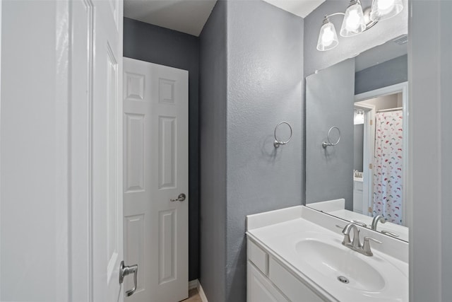 full bathroom featuring vanity, a chandelier, and a textured wall