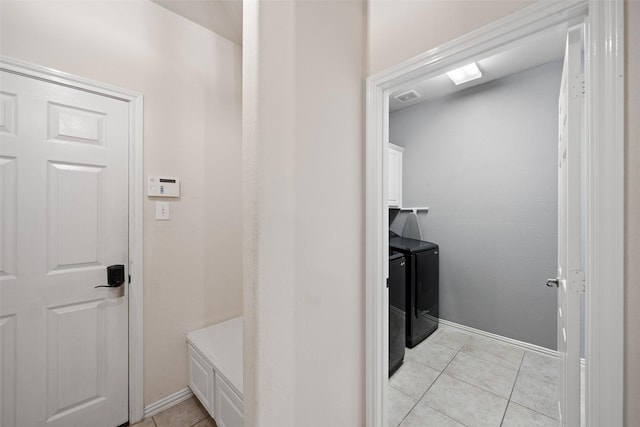 clothes washing area featuring washer and dryer, cabinet space, light tile patterned flooring, and baseboards