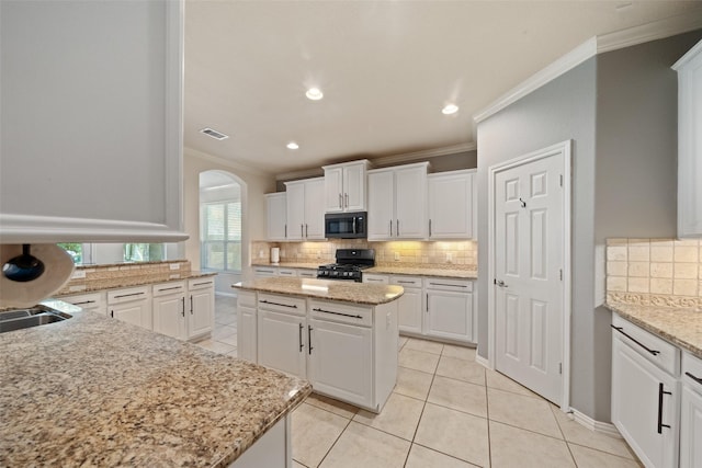 kitchen with black appliances, crown molding, decorative backsplash, arched walkways, and white cabinets