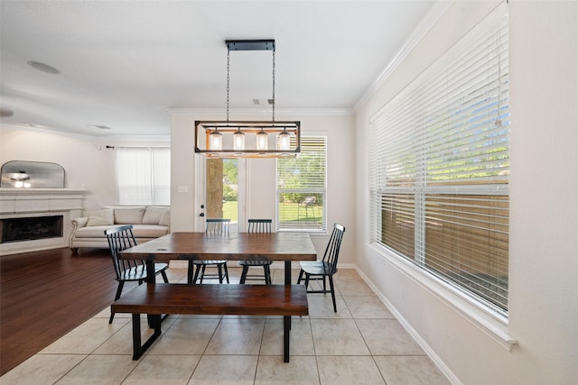 dining space with light tile patterned flooring, crown molding, a fireplace, and baseboards