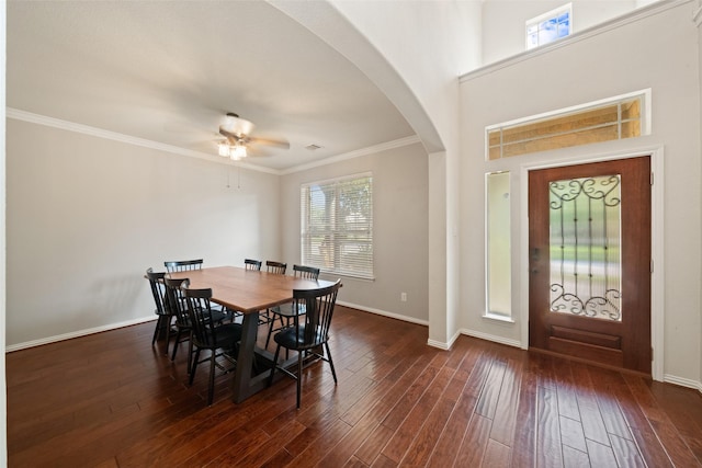 dining room with wood finished floors, ceiling fan, arched walkways, baseboards, and ornamental molding