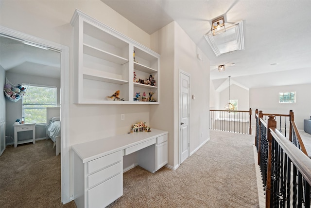 hall featuring light colored carpet, an office area, attic access, and baseboards