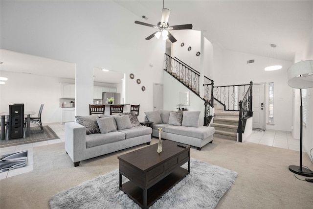 living area with light carpet, stairway, high vaulted ceiling, a ceiling fan, and light tile patterned flooring