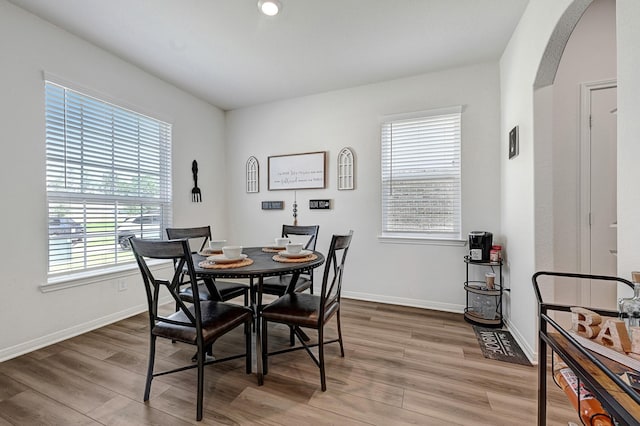 10707 Lost Maples Dr, Cleveland, TX 77328 - dining space featuring healthy amount of natural light, arched walkways, wood finished floors, and baseboards