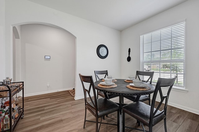 10707 Lost Maples Dr, Cleveland, TX 77328 - dining space with arched walkways, light wood finished floors, and baseboards