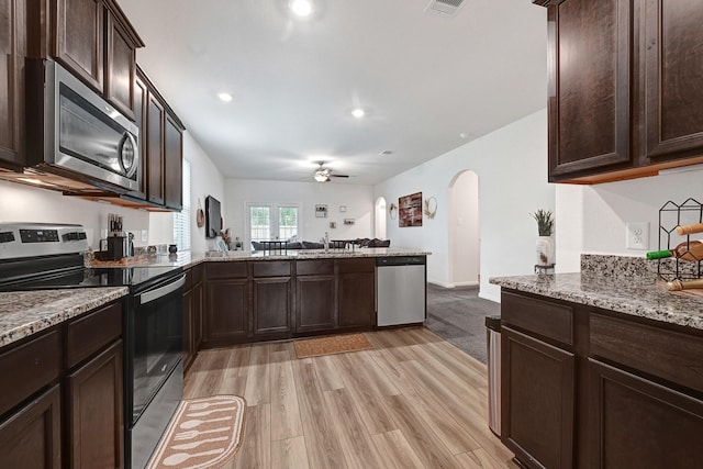 10707 Lost Maples Dr, Cleveland, TX 77328 - kitchen featuring stainless steel appliances, arched walkways, dark brown cabinetry, ceiling fan, and light wood-style floors