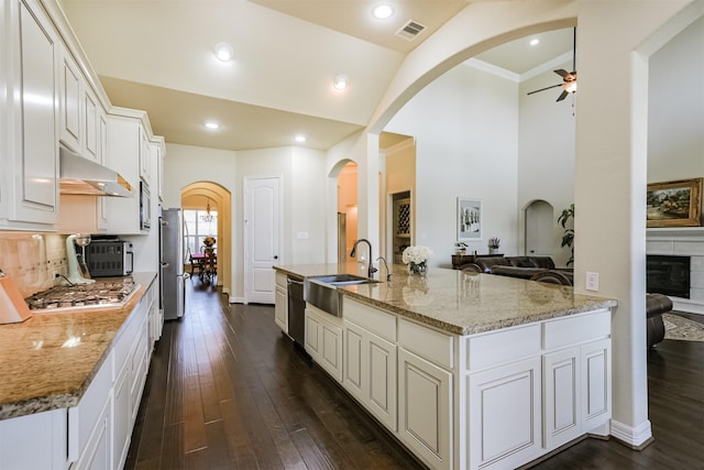 23615 Dolci Ln, Richmond, TX 77406 - kitchen with a sink, under cabinet range hood, arched walkways, a ceiling fan, and stainless steel appliances