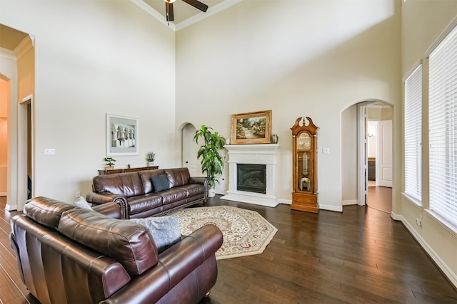 23615 Dolci Ln, Richmond, TX 77406 - living room featuring arched walkways, a ceiling fan, a high ceiling, dark wood-style floors, and ornamental molding