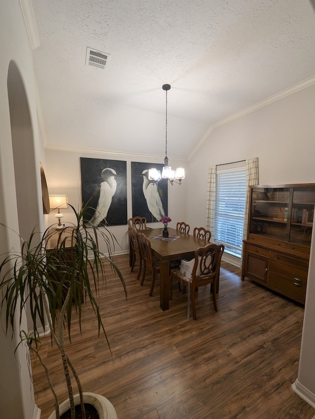 dining space with ornamental molding, lofted ceiling, dark wood-type flooring, a textured ceiling, and arched walkways