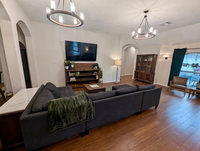 living room featuring a chandelier, arched walkways, and wood finished floors