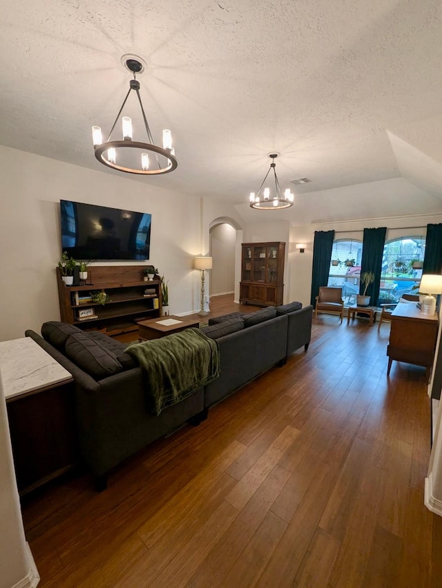living room with a chandelier, arched walkways, a textured ceiling, and hardwood / wood-style floors