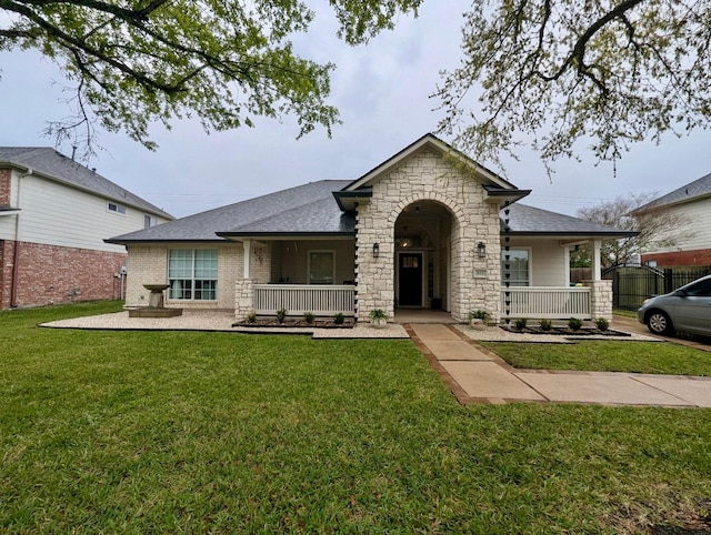 view of front of house featuring covered porch, a front lawn, and stone siding