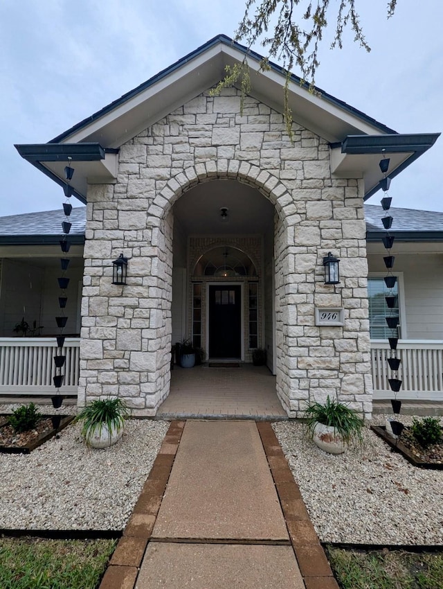 doorway to property with a porch and stone siding