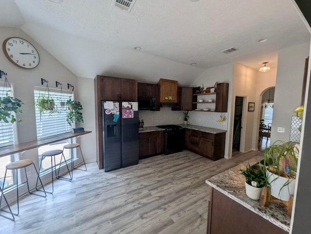 kitchen featuring black appliances, open shelves, lofted ceiling, arched walkways, and backsplash