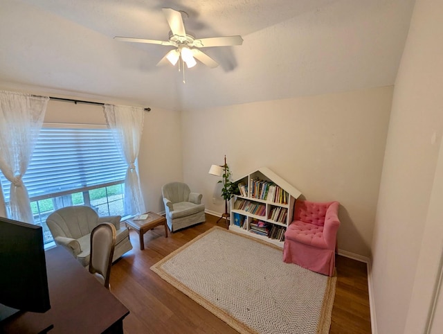 living area featuring ceiling fan, wood finished floors, a desk, and baseboards