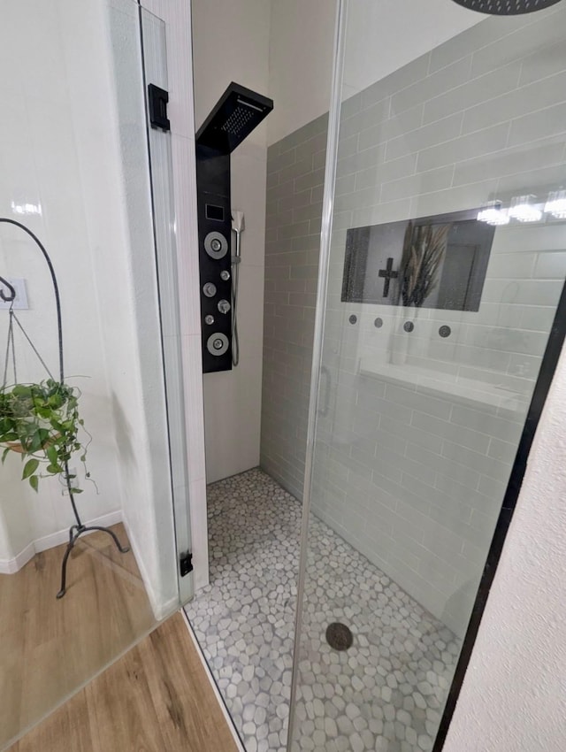 bathroom with tiled shower and wood finished floors