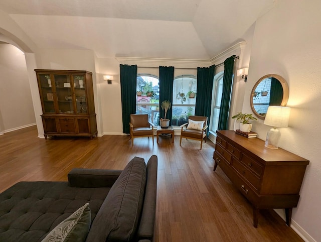 living area featuring arched walkways, wood finished floors, lofted ceiling, and baseboards