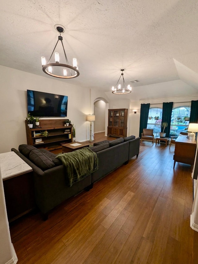 living room featuring a chandelier, arched walkways, a textured ceiling, and wood-type flooring