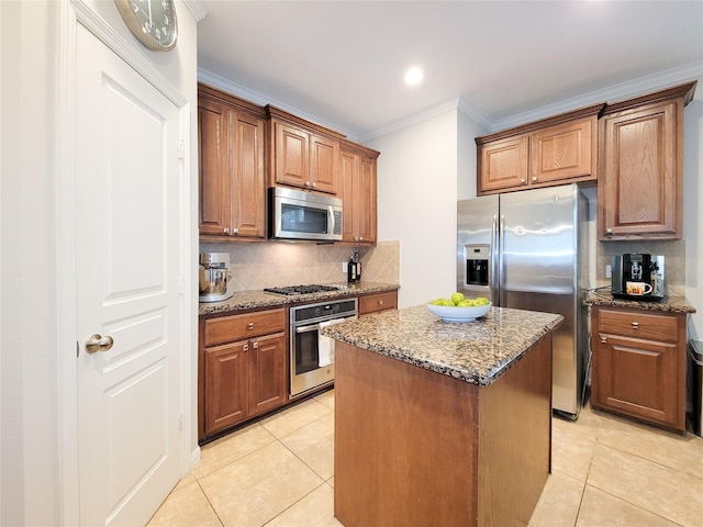 1241 Prince St, Houston, TX 77008 - kitchen featuring appliances with stainless steel finishes, ornamental molding, light tile patterned floors, dark stone counters, and a center island