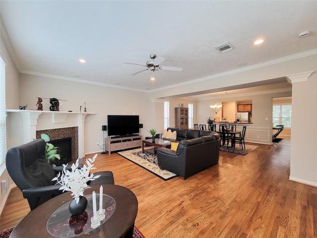 1241 Prince St, Houston, TX 77008 - living room featuring light wood-style flooring, a fireplace, ceiling fan, decorative columns, and a chandelier