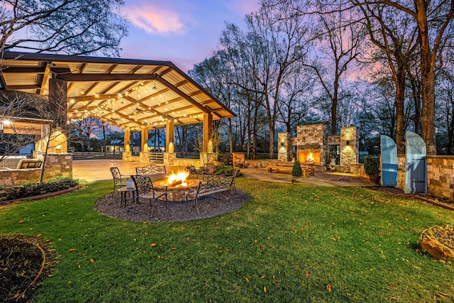 3113 Saddlebrook Ln, Katy, TX 77494 - view of grassy yard featuring an outdoor stone fireplace, a patio area, and an outdoor fire pit