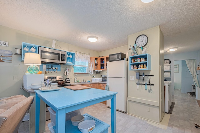 333 9th St, San Leon, TX 77539 - kitchen featuring appliances with stainless steel finishes, open shelves, a textured ceiling, light countertops, and washing machine and clothes dryer