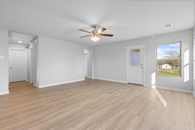 unfurnished living room with attic access, a ceiling fan, light wood finished floors, and baseboards