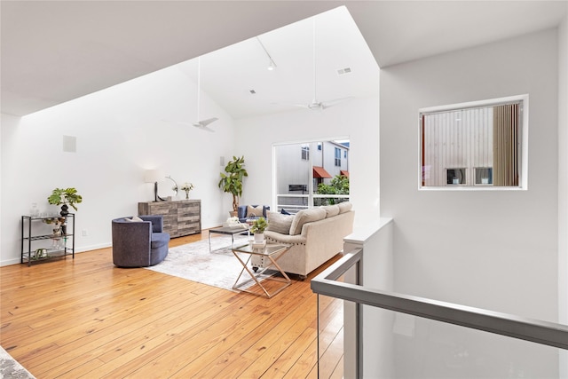 living area featuring light wood-style floors, a ceiling fan, and high vaulted ceiling